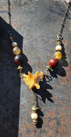 a necklace with various beads and charms hanging from it's sides on a stone surface