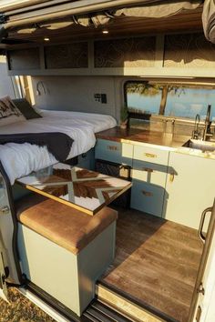 the inside of a camper with a bed, sink and kitchenette in it