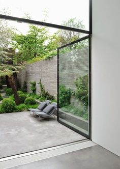 an empty patio with chairs and trees in the back ground, surrounded by concrete walls