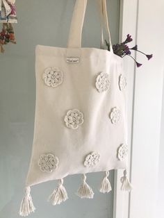 a white bag hanging from the side of a door with tassels on it