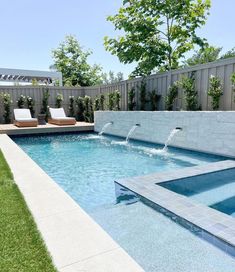 an outdoor swimming pool with water features and seating area in the back yard, surrounded by grass