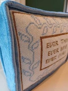 a close up of a blue pillow on a white counter top next to a window