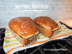 two loafs of bread sitting on top of a kitchen towel next to an oven