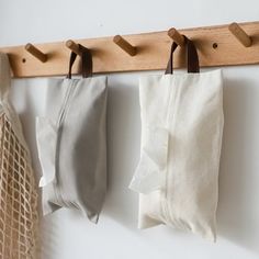 three bags are hanging on a wall with pegs to hang them from the hooks