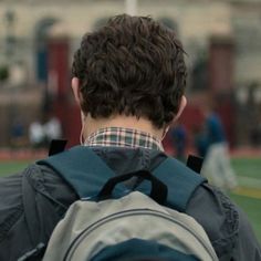 the back of a man's head with a backpack in front of him on a baseball field