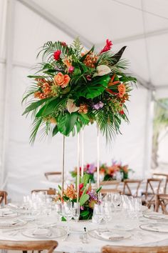 an arrangement of flowers and greenery in tall vases on top of a table