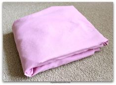 a pink blanket is laying on the floor in front of a carpeted area with no one around it