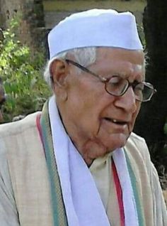 an old man with glasses and a white hat is talking to someone in front of him