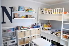 a bedroom with bunk beds and toys on the shelves in front of it, along with other children's furniture