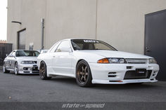 two white cars parked next to each other in front of a building