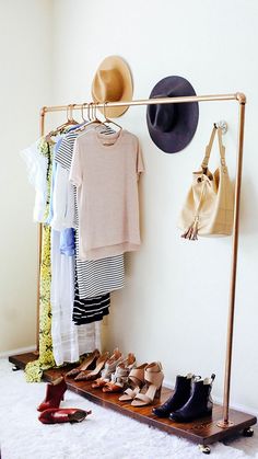 a rack with hats, shoes and purses hanging on it next to a wall