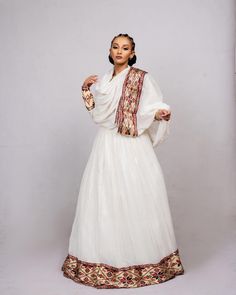 This stunning traditional dress features a beautiful combination of Menen fabric in a deep shade of red, with a Shimena fabric bottom that adds a touch of elegance and sophistication. The dress is designed to be both flattering and comfortable, with a fitted bodice that accentuates the curves and a flowing skirt that drapes gracefully over the hips and legs. The intricate Tilf embroidery design adds a touch of glamour and sophistication to the garment, with delicate beadwork that creates a stunn Eritrean Dress, Ethiopian Wedding, Ethiopian Clothing, Habesha Dress, Bloom Dress, Ethiopian Traditional Dress, Ethiopian Women, Ethiopian Dress, Habesha Kemis