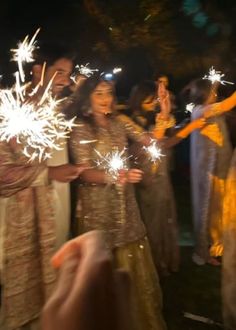 people are holding sparklers in their hands