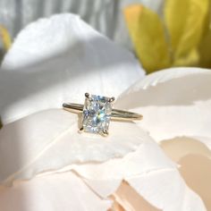 a diamond ring sitting on top of a white flower