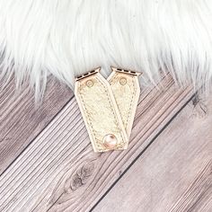 a pair of leather gloves sitting on top of a wooden floor next to a white fur