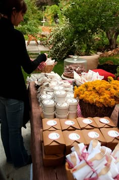 a woman standing next to a table filled with boxes and flowers