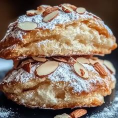 two cookies stacked on top of each other covered in powdered sugar and almonds