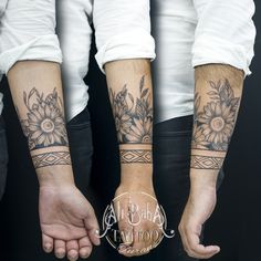 two people holding hands with sunflowers on their arms and wristbands tattooed