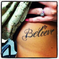 a woman's stomach with the word believe written on it and a diamond ring in her hand