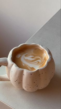 a white ceramic cup filled with liquid sitting on top of a counter