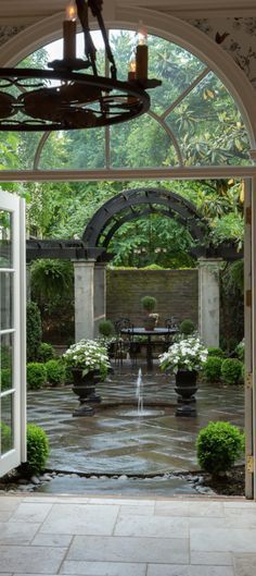 an open door leading to a patio with potted plants and a fountain in the center