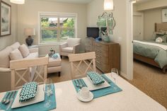 a living room filled with furniture next to a bed and a table in front of a window