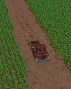 a red truck driving down a dirt road next to a field full of green plants