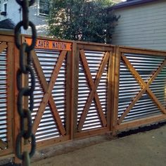 a wooden fence with metal slats on the top and bottom, in front of a house