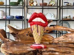 a wooden table topped with an ice cream cone covered in red and white frosting