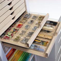 an open drawer with lots of crafting supplies in it and some drawers on the bottom