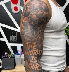 a man with a tattoo on his arm that says the world is yours