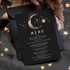 a black menu card with gold stars and a teddy bear on the table next to it