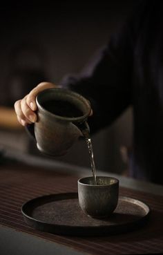 a person pouring water into a cup on top of a plate