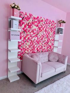 a living room decorated in pink and white with flowers on the wall behind the couch