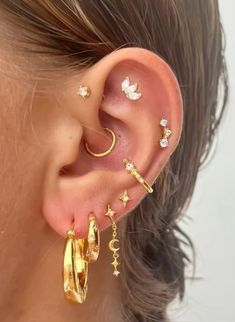 a close up of a person wearing gold ear cuffs with stars and moon designs on them