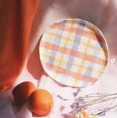 two oranges sitting on top of a table next to an empty plate and flowers