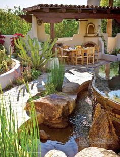 an outdoor dining area with rocks and water features in the foreground, surrounded by cactuses and succulents