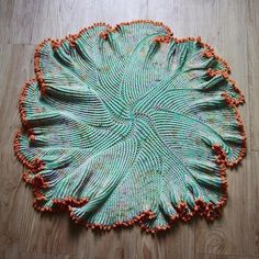 a green and orange woven object on a wooden floor