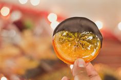 a person holding up an orange slice in their hand