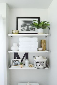 a bathroom with white shelves and pictures on the wall