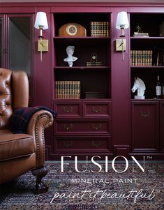 a brown leather chair sitting in front of a book shelf filled with books and vases