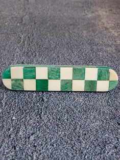 a green and white checkered skateboard laying on the ground