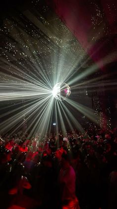 a large group of people in a dark room with bright lights on the ceiling and floor