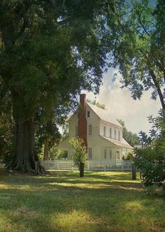 a large white house sitting in the middle of a lush green field next to trees