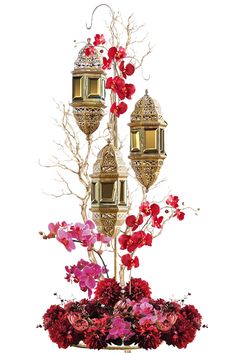 a vase filled with flowers next to two golden lanterns on top of a white table