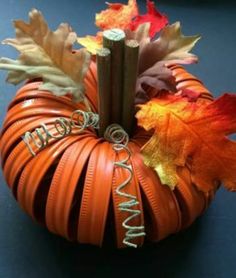 an orange pumpkin decorated with leaves and the word autumn written on it's side