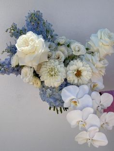 a bouquet of white and blue flowers hanging from a wall