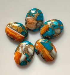 five turquoise and orange stones sitting on top of a white table next to each other