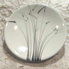 a white plate with black designs on it sitting on a marble counter top next to a wall