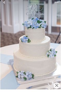 a white wedding cake with blue flowers on it